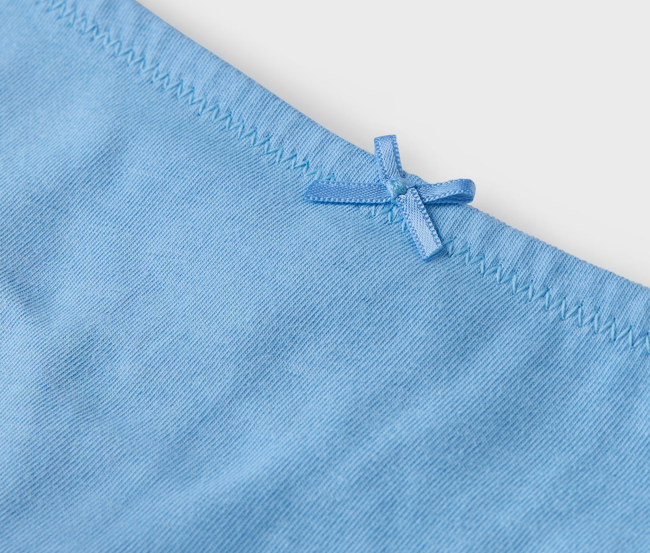 Détail d'une culotte bleu clair avec un nœud.