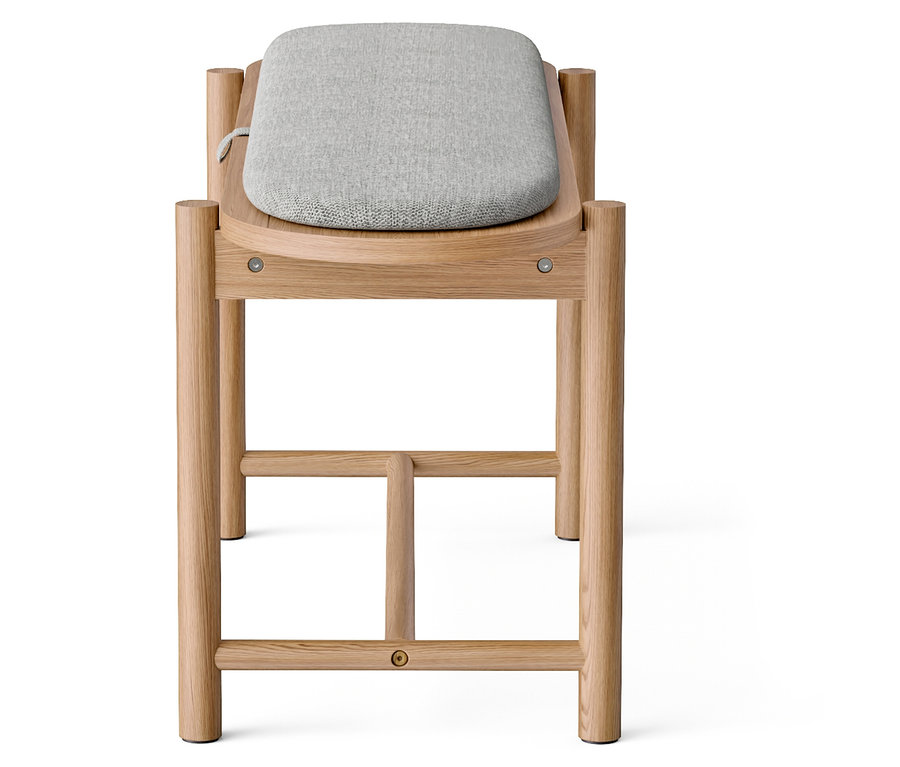 Gros plan d'un tabouret en bois avec une assise en tissu gris.