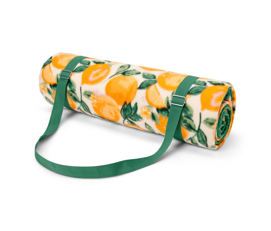 Une nappe de pique-nique XL enroulée avec un motif d'oranges et des sangles vertes.