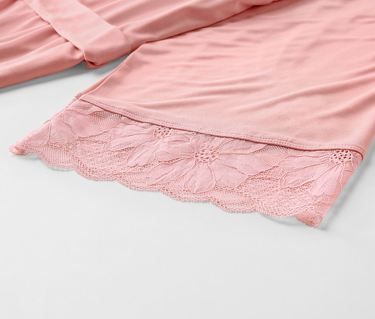 Détail d'une robe de chambre rose avec de la dentelle.