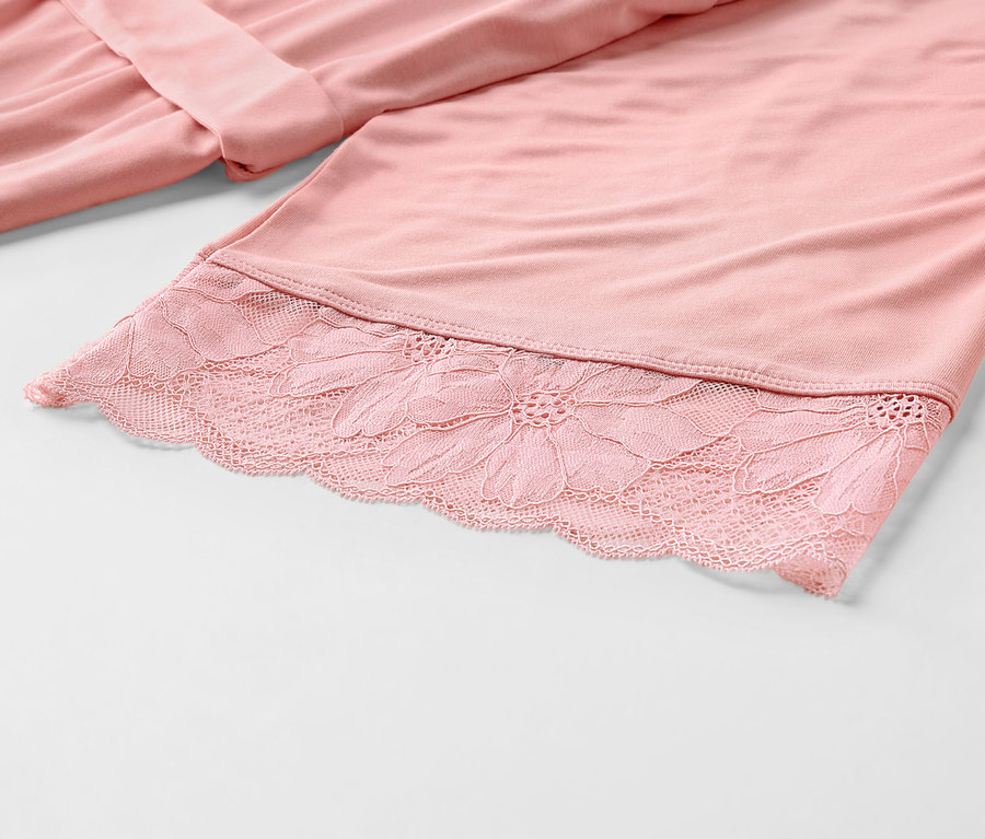 Détail d'une robe de chambre rose avec de la dentelle.