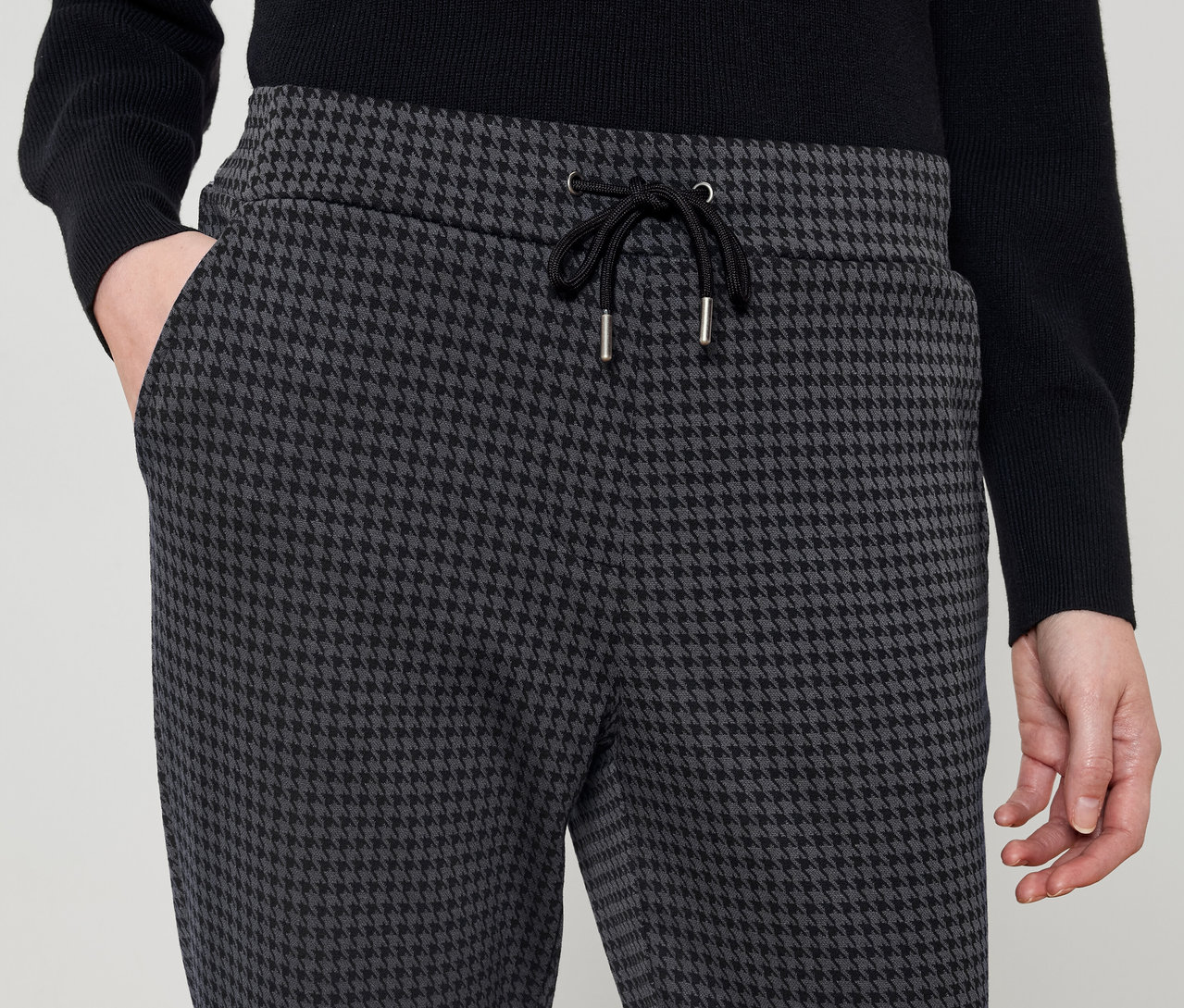 Une personne porte un pantalon à motif pied-de-poule avec un cordon de serrage noir.