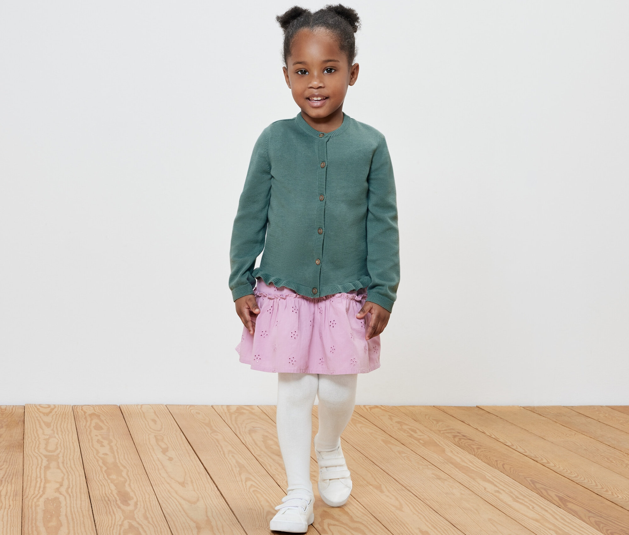 Fillette souriante posant en veste en maille pour enfant.