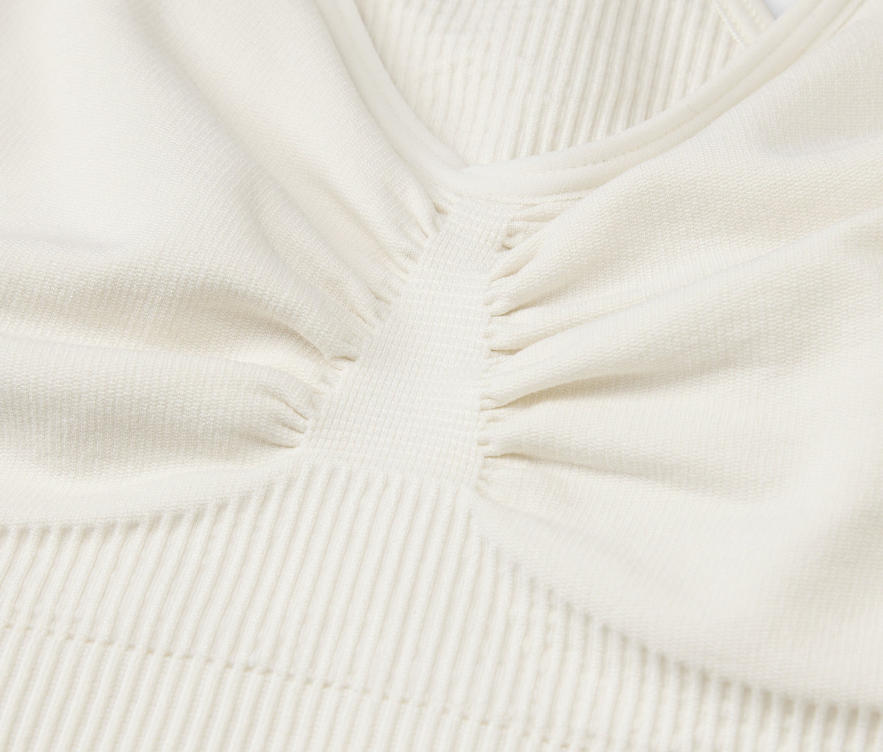 Gros plan sur le tissu texturé d'un haut de sport crème.