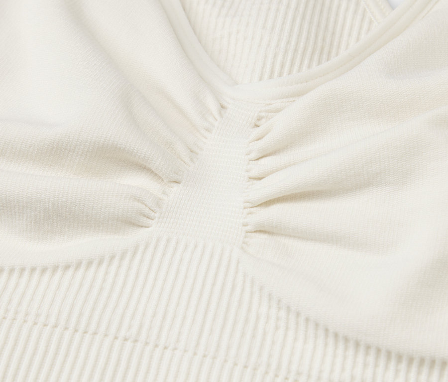 Gros plan sur le tissu texturé d'un haut de sport crème.