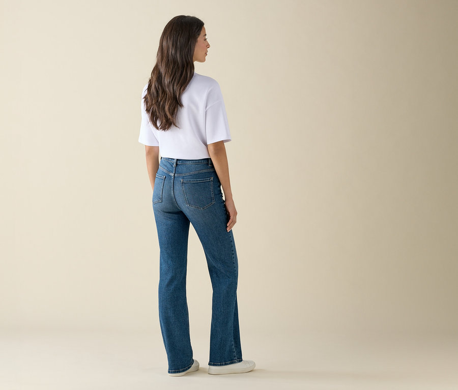 Une femme, vue de dos, porte un jean bleu et un t-shirt blanc.