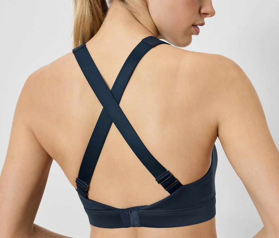 Vue arrière d'une femme portant un soutien-gorge de sport bleu marine dont les bretelles se croisent dans le dos. Soutien-gorge de sport.