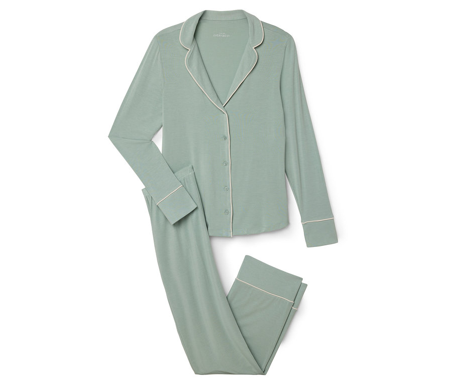 Un pyjama vert avec une bordure blanche posé sur un fond blanc.