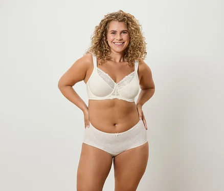 Une femme aux cheveux bouclés pose en sous-vêtements.