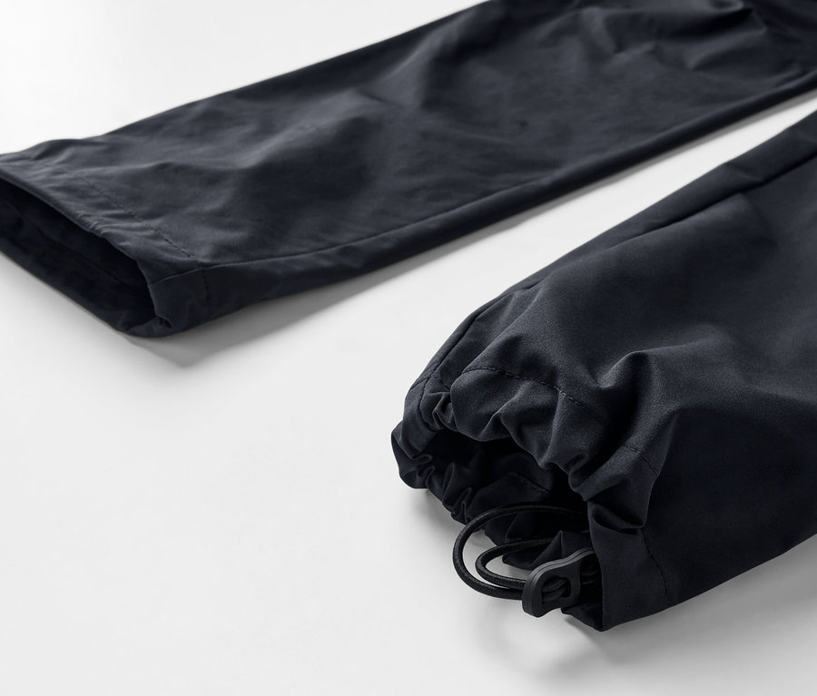 Gros plan sur un pantalon fonctionnel 2 en 1 noir avec cordon de serrage à l'ourlet.