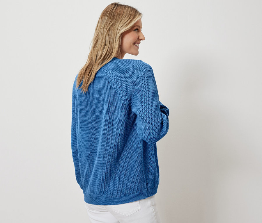 Femme posant en cardigan ouvert et jean blanc.