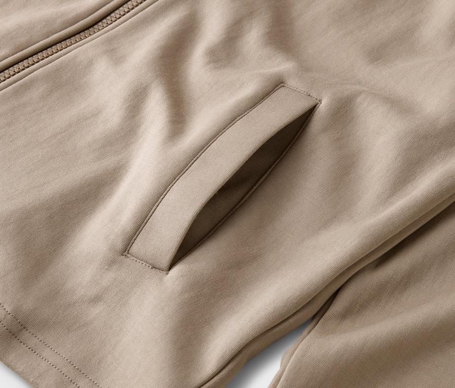 Gros plan d'une veste marron clair avec fermeture éclair et poche.