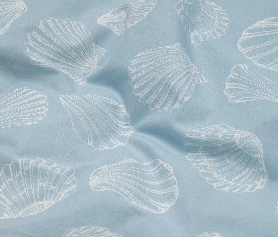 Gros plan d'un tissu bleu clair avec un motif de coquillages blancs et de légers plis.