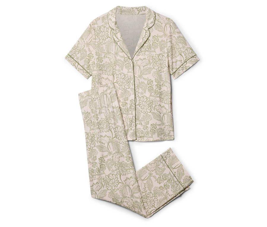 Un pyjama deux pièces avec un fond rose clair et un motif floral vert est posé sur un fond blanc.
