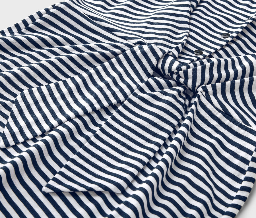 Gros plan sur une chemise rayée bleu et blanc avec patte de boutonnage et détail noué.
