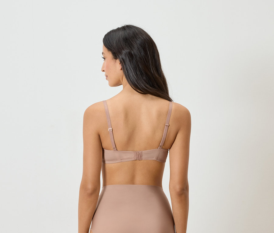 Vue arrière d'une femme aux cheveux foncés portant un soutien-gorge et des sous-vêtements couleur chair.