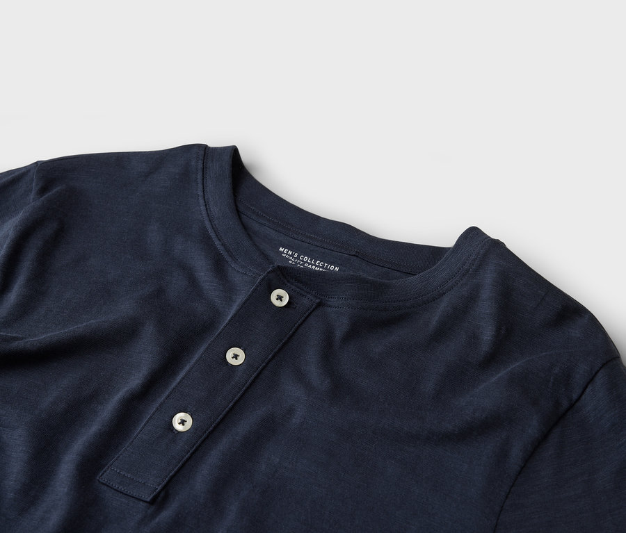 Gros plan d'un t-shirt Henley bleu marine avec trois boutons.