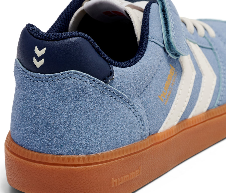 Gros plan d'une basket Hummel bleu clair avec une semelle marron et une fermeture velcro.