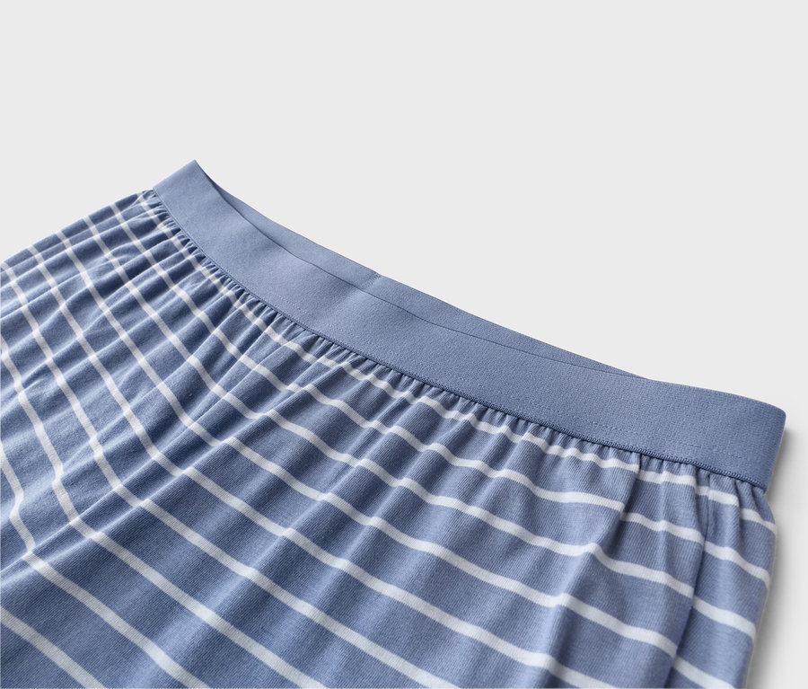 Gros plan d'un pantalon de pyjama rayé bleu et blanc avec une taille élastique bleue.