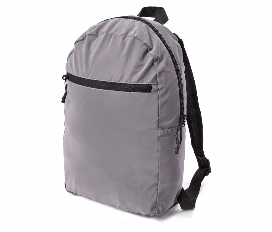 Sac à dos gris avec fermeture éclair et bretelles noires, posé de côté sur fond blanc.