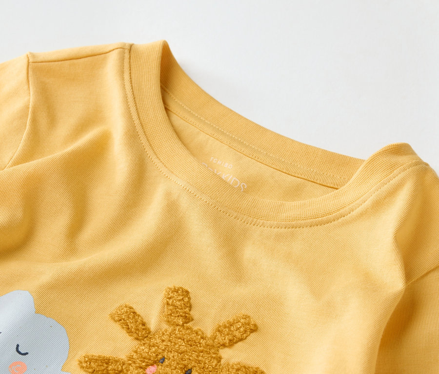Gros plan sur un t-shirt jaune pour enfants avec un motif de nuage et de lapin.