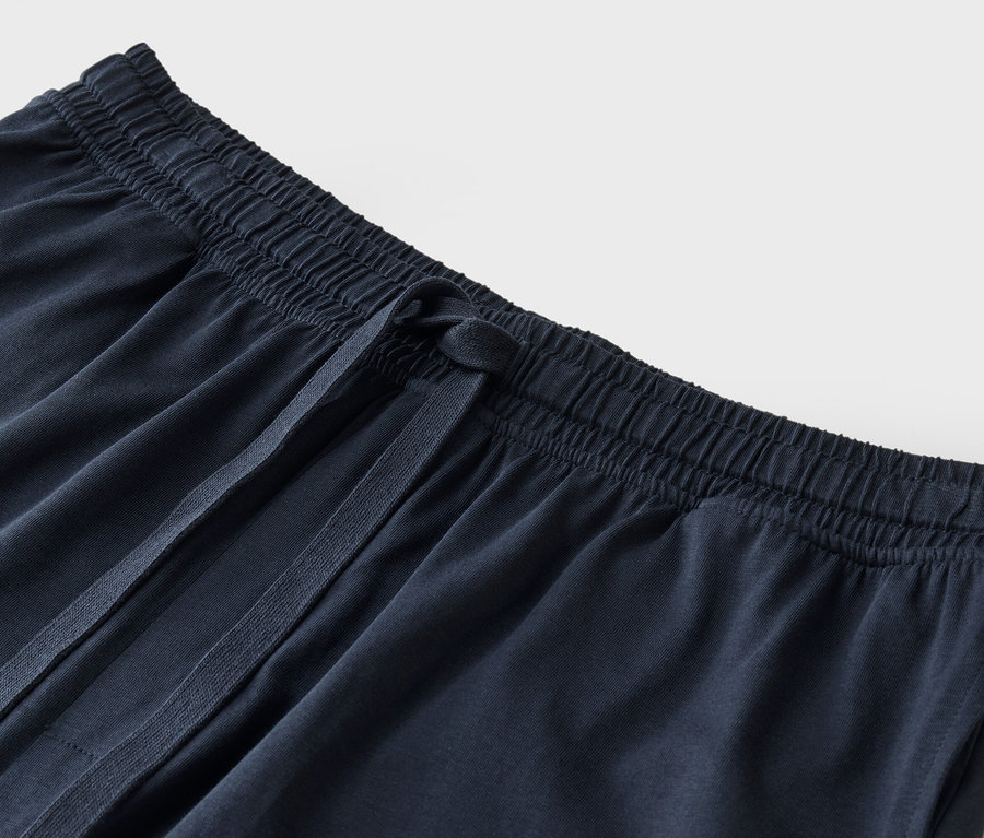 Gros plan d'un pantalon de survêtement en tissu bleu foncé avec cordon de serrage.