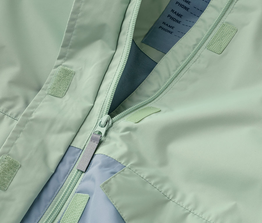 Gros plan d'une veste vert menthe ouverte avec fermeture éclair et accents bleu clair.