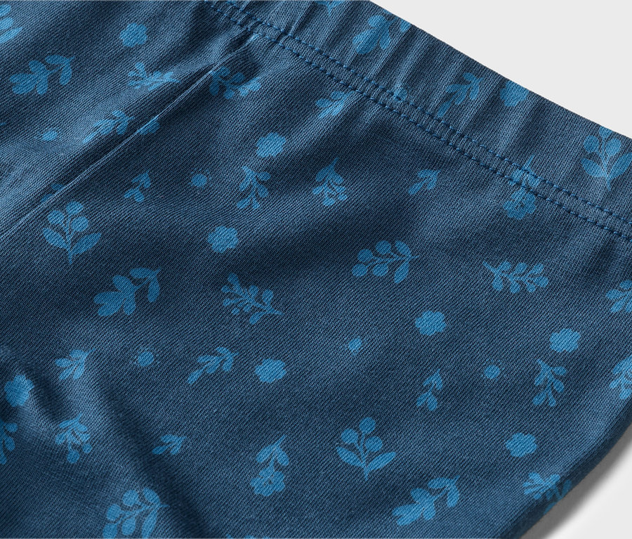 Gros plan d'un legging bleu marine avec des motifs floraux et de feuilles bleu clair et une taille élastique.