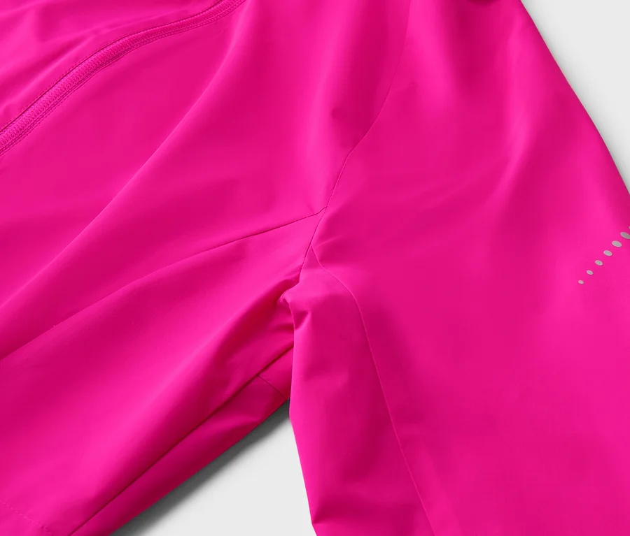 Gros plan sur une veste rose avec fermeture éclair et points réfléchissants sur la manche.