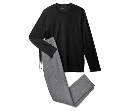 Un haut noir à manches longues est posé à côté d'un pantalon de jogging gris sur un fond blanc.