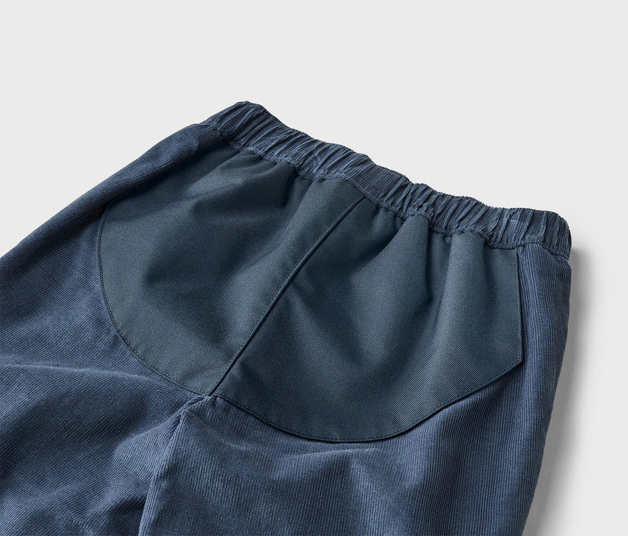 Gros plan d'un pantalon en velours côtelé bleu avec une taille élastique et une poche arrière plaquée.