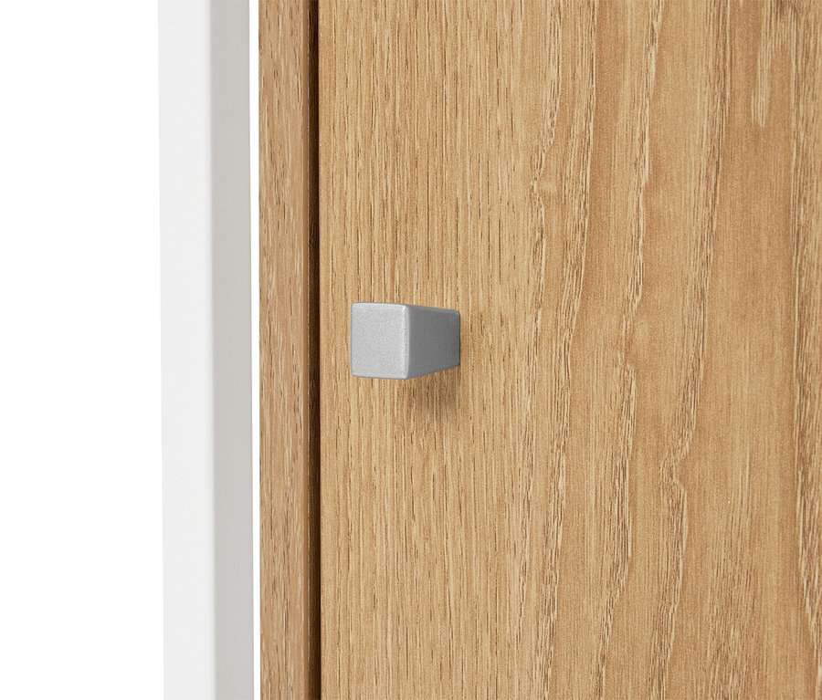Gros plan sur une porte d'armoire en bois clair avec une poignée argentée en forme de parallélépipède rectangle.