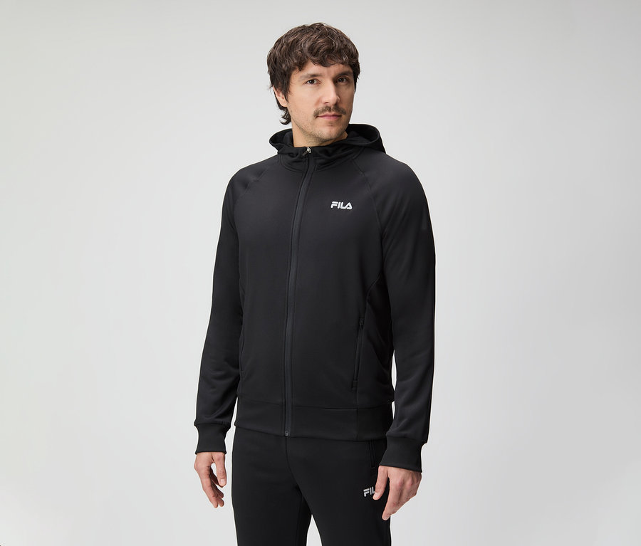 Un homme avec une moustache porte un survêtement Fila noir à capuche.