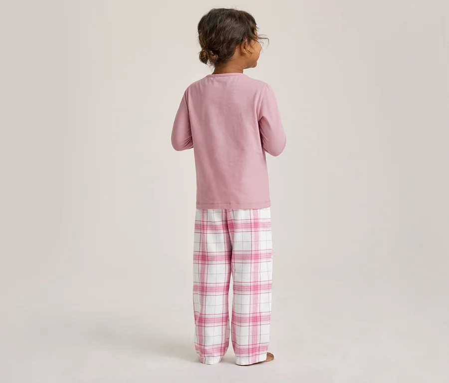 Enfant de dos, portant un pyjama rose à manches longues et un pantalon de pyjama à carreaux roses et blancs.