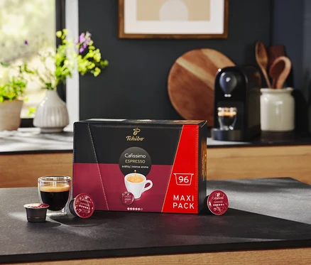 Cafetière Cafissimo pure+, noire et un paquet de 96 capsules Cafissimo Espresso kräftig (corsé) sur un comptoir.