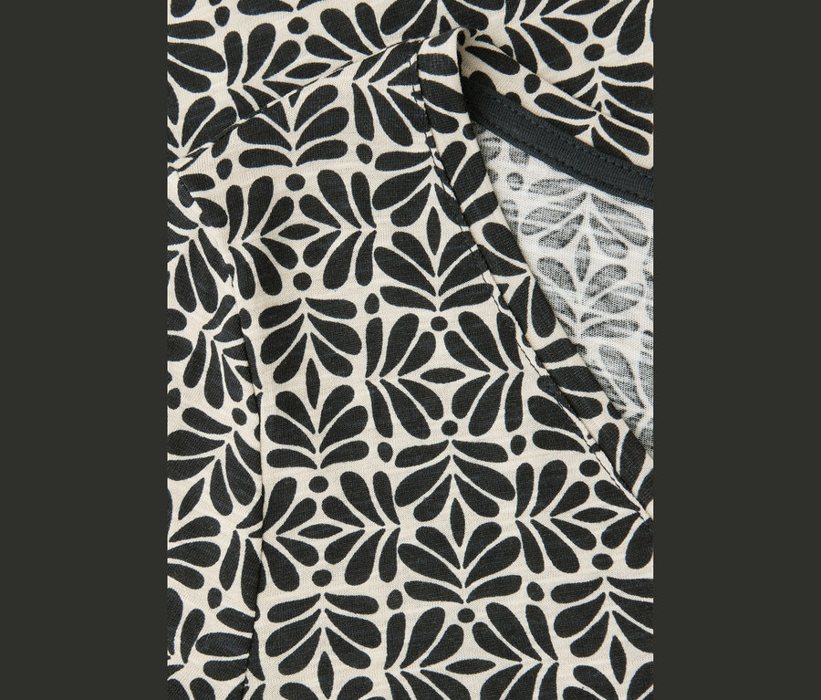 Gros plan sur un t-shirt Street One avec motif noir à feuilles et pois et encolure en V.