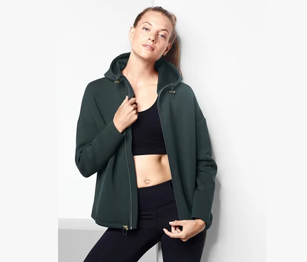 Une femme portant une veste scuba, un soutien-gorge de sport et un legging.