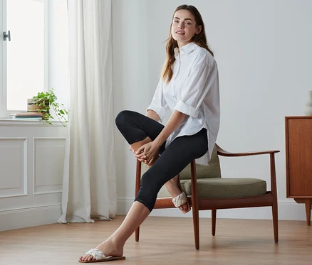 Femme assise sur une chaise portant un legging 3/4 noir avec bordure en dentelle.