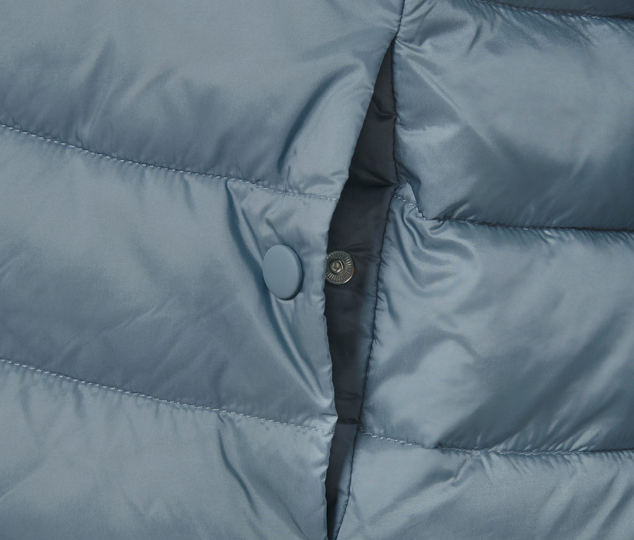 Détail d'une veste matelassée avec poche et bouton pression.