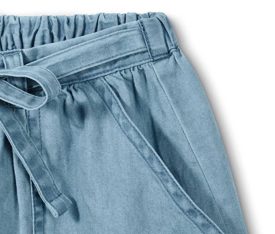 Gros plan sur une jupe en denim de coton avec une ceinture à nouer et une poche.