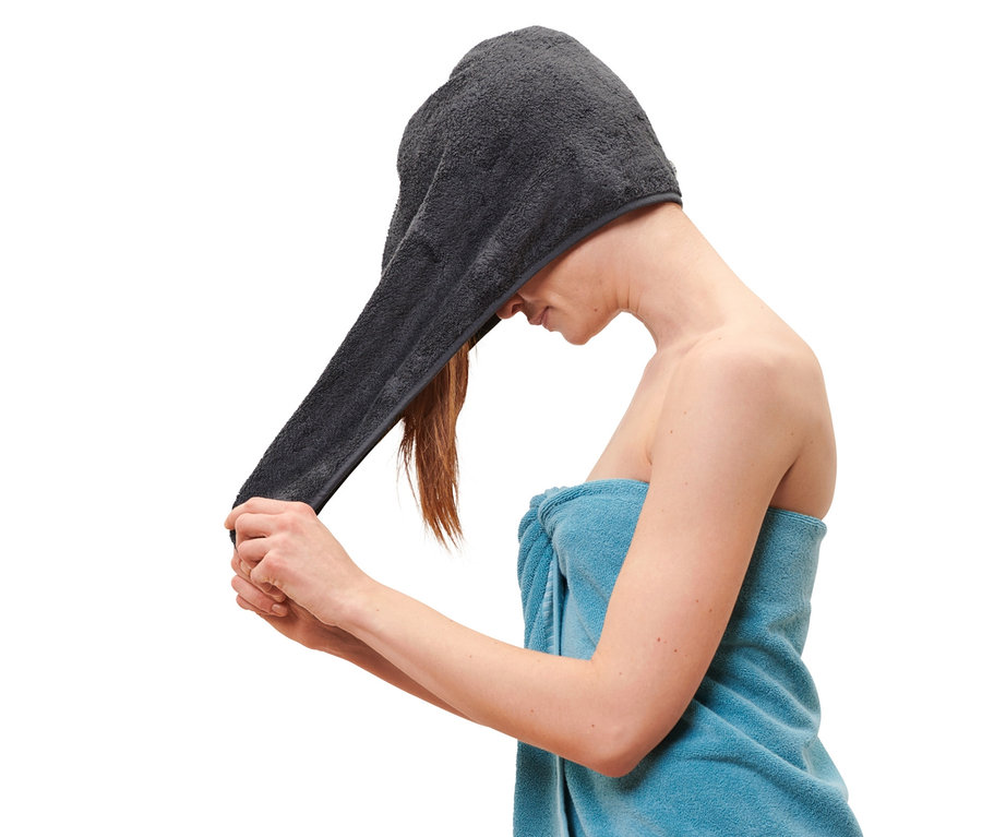 Femme mettant une serviette turban anthracite sur sa tête.