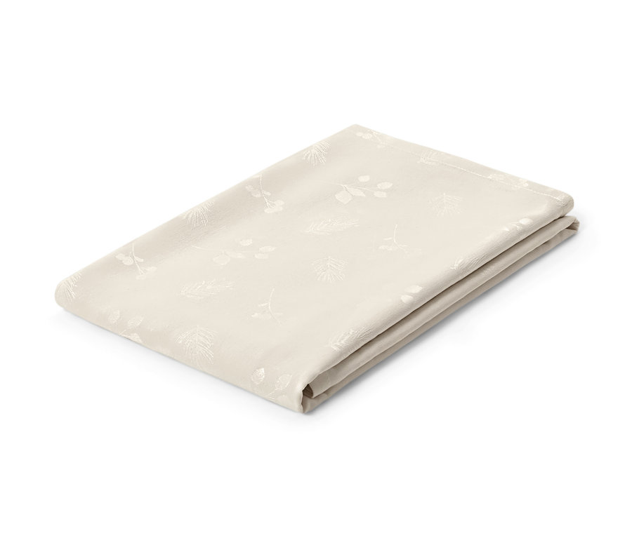 Nappe en jacquard crème pliée avec motif de feuilles.