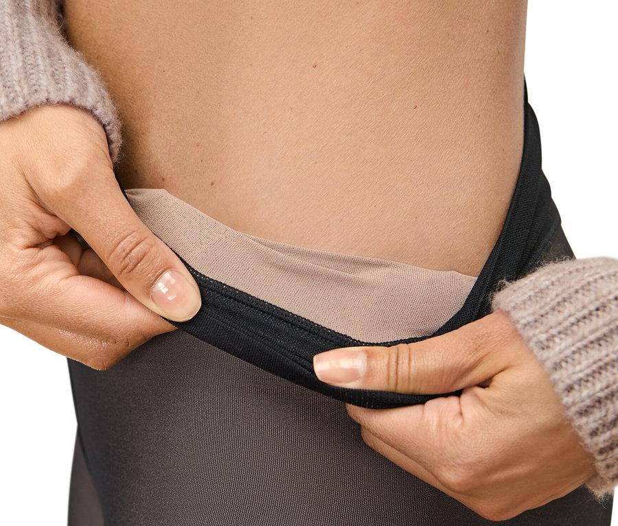 Une femme tient des collants fins 50 DEN en aspect transparent à la taille.