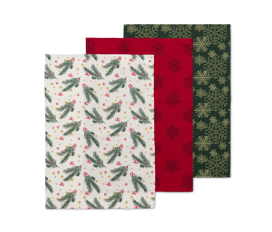 Trois linges de cuisine : un avec un motif de branches de sapin, un rouge avec des flocons de neige, un vert avec des flocons de neige dorés.