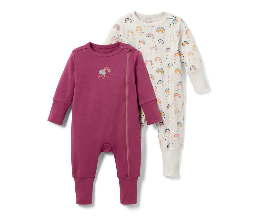 Deux pyjamas pour bébé avec motif arc-en-ciel. L'un est violet avec un arc-en-ciel sur la poitrine, l'autre blanc avec un imprimé arc-en-ciel.