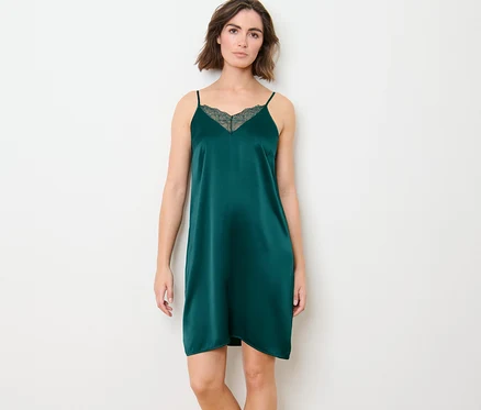 Une femme pose devant un fond blanc et porte un déshabillé en pure soie.