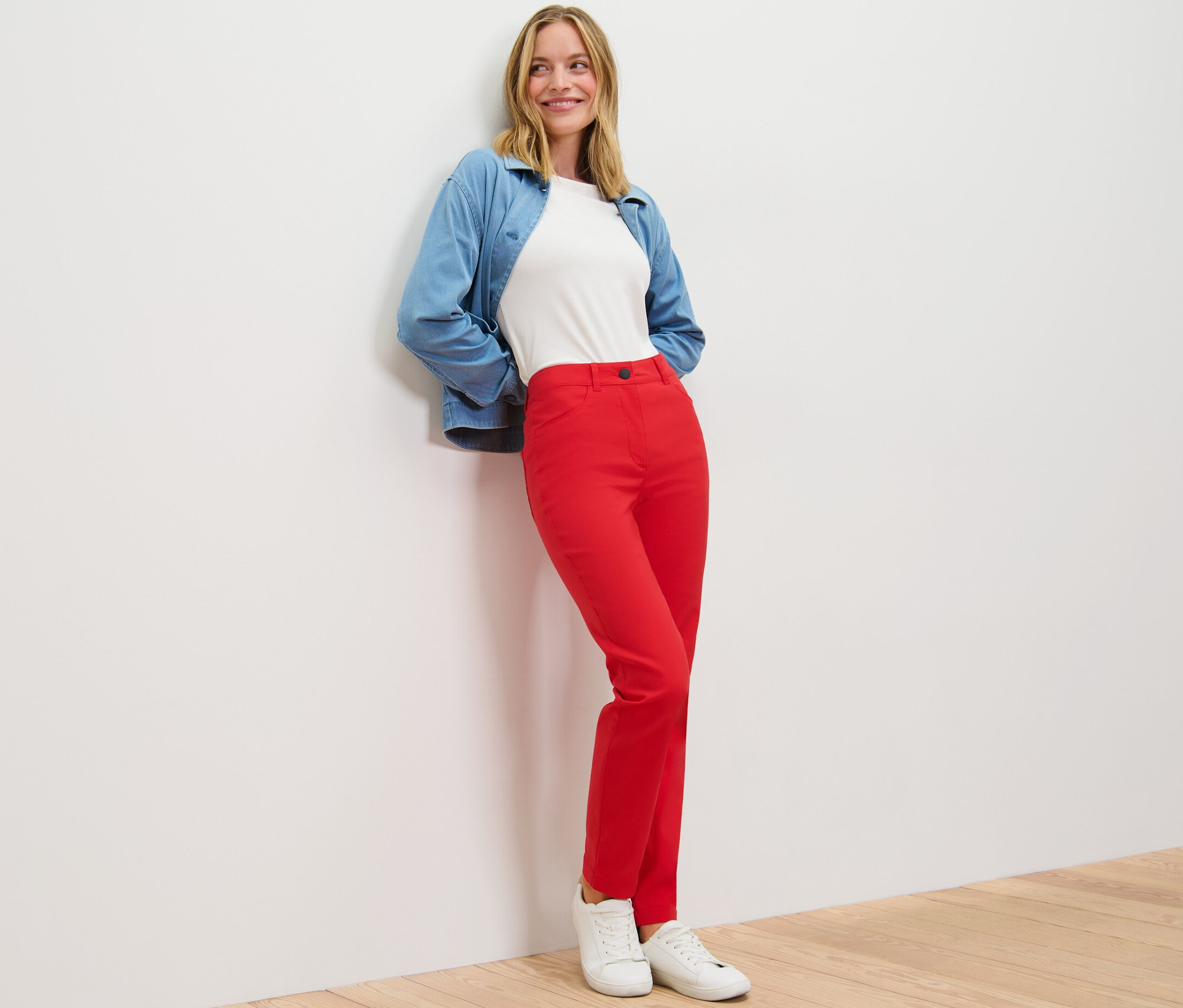 Femme posant en pantalon en bengaline rouge, t-shirt blanc et veste bleue.