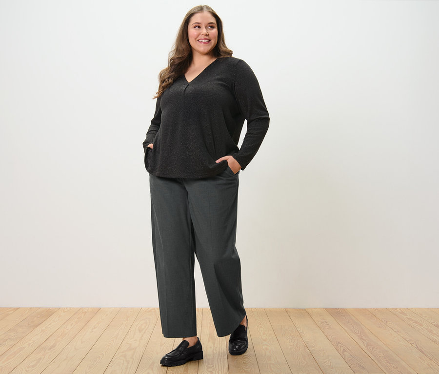 Femme posant en pantalon tissé confortable et blouse scintillante.