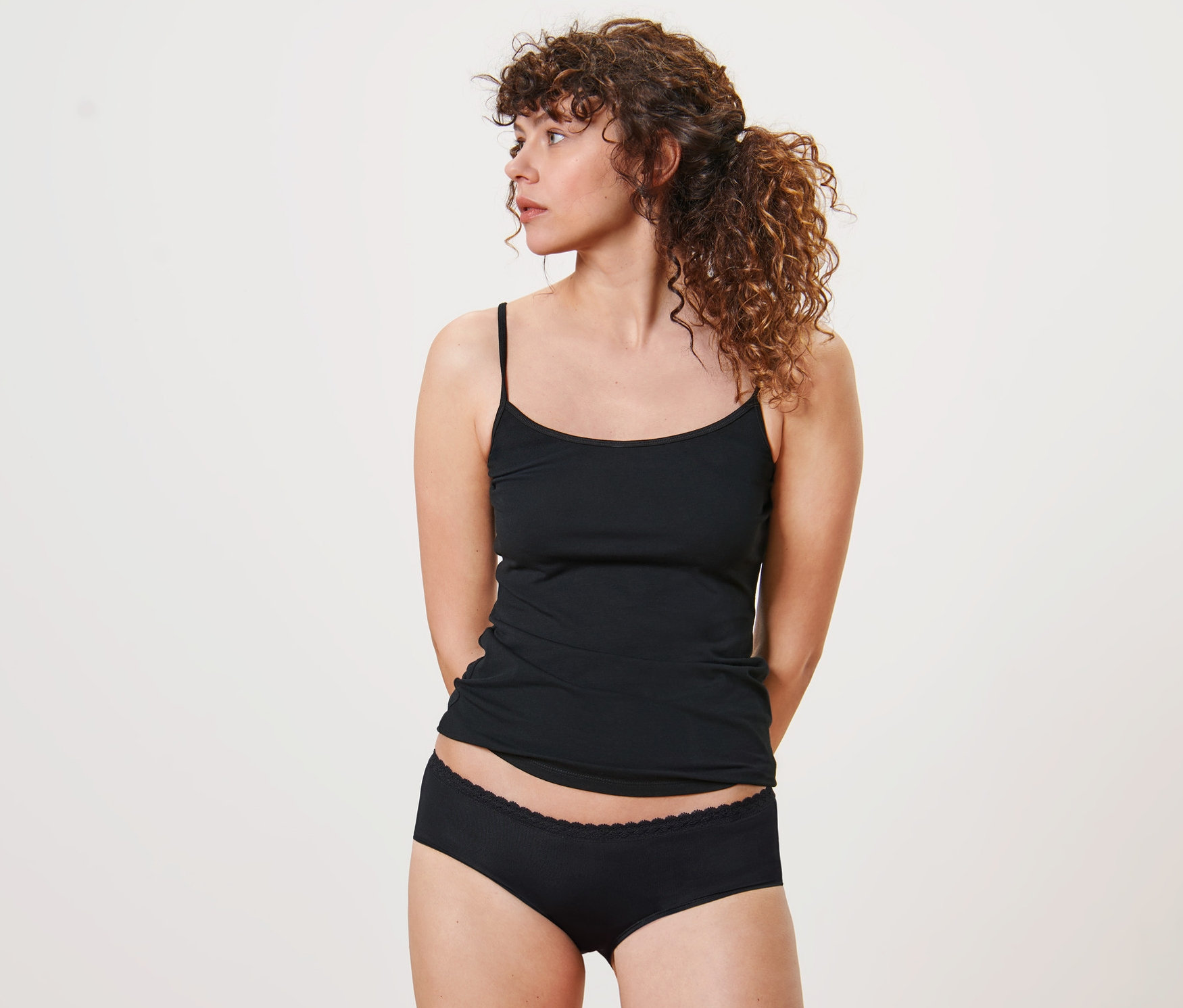 Une femme porte 5 culottes noires et un débardeur.