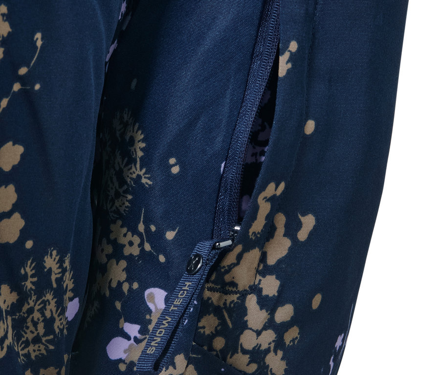 Détail d'une veste de ski à fermeture demi-zippée avec poche zippée ouverte.